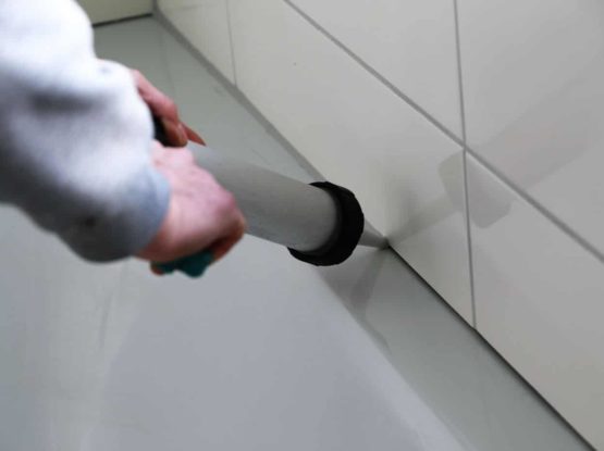 Man sealing a bath or basin with silicone